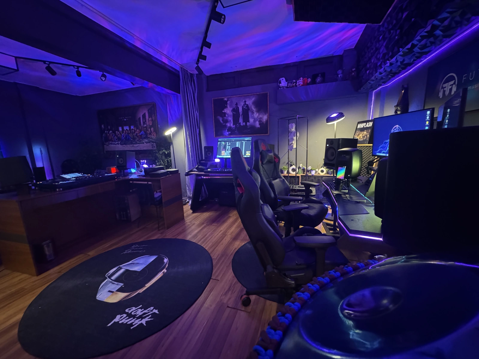 Future Focus stüdyosunun geniş görünümünde DJ kabini, bilgisayarlı çalışma masaları ve mor stüdyo ışıkları